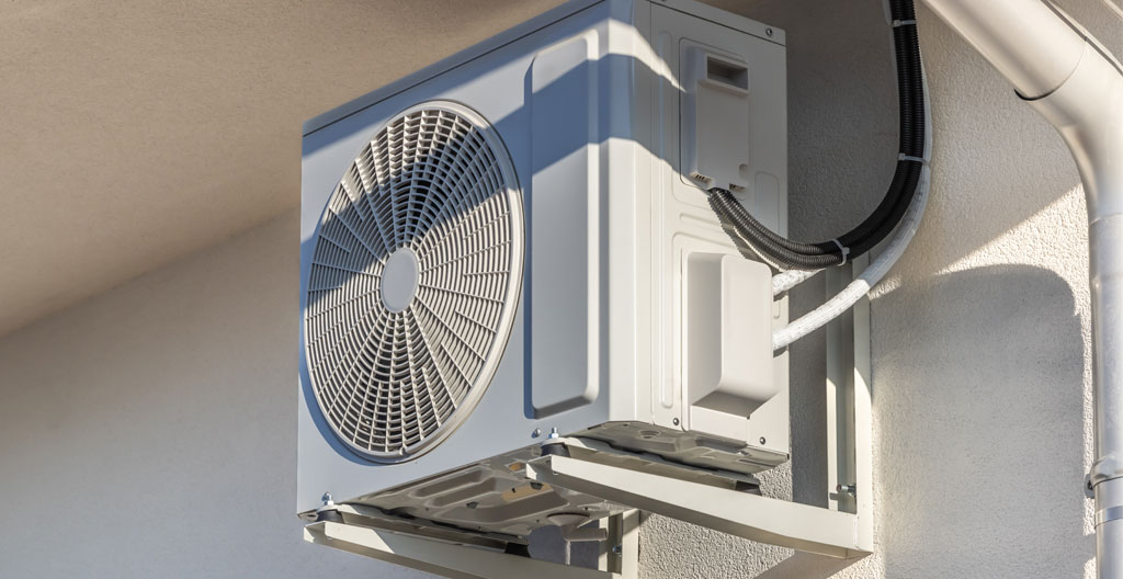 Vue large d'une façade d'immeuble résidentiel français contemporain avec plusieurs unités extérieures de pompe à chaleur discrètement installées sur les balcons